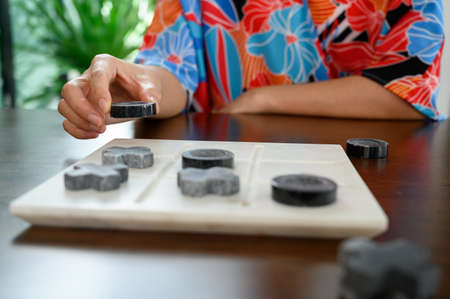 Marble Tic Tac Toe or OX board game on wooden table.  woman playing tic tac toe game. concept of...