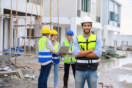 Portrait ofÂ young attractive construction man smiling bearded in vest with white helmet standing...