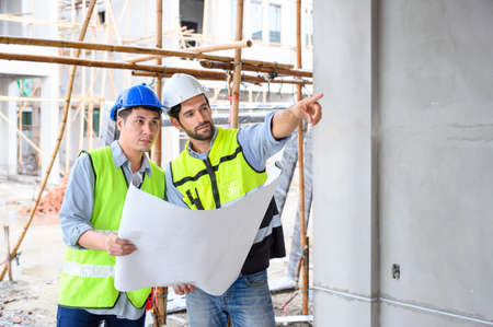 Construction engineer and architect check plan working with the blueprint on construction site. They...