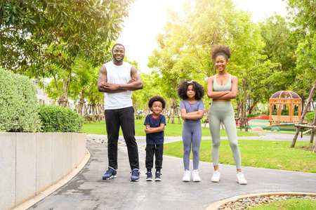 Portrait of Happy African American smiling family resting and having fun after workout outdoors, wearing sports clothes. father, mother and child daughterの写真素材