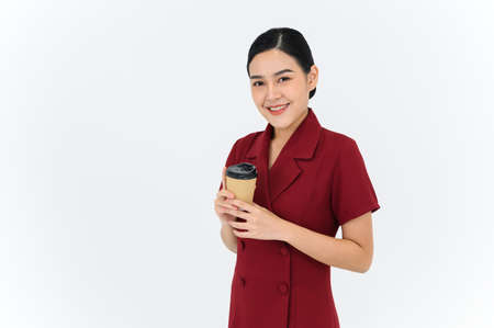 Look at the camera for a portrait of a young businesswoman posing with paper cup of coffee or tea,...