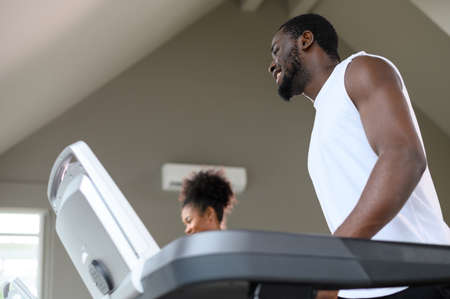 Black African American couple running on the treadmill at fitness club. Healthy lifestyle, training...