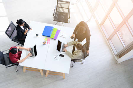 Top view of Business people group meeting in office. Aerial view with professional businesswomen and businessmen working in team conference with project planning document on the meeting tableの写真素材