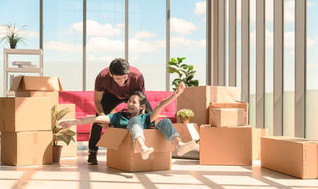 Happy young asian couple smiling in love and having fun riding inside cardboard box. celebrating moving to new home conceptの写真素材