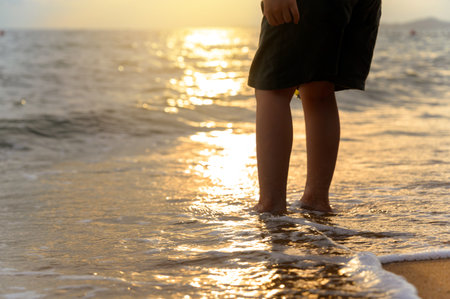 Close-up boy Legs on sandy beach seaside in summer at sunset time. Kid playing on the beach. summer...