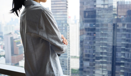 Side view of pensive woman standing looking out of window enjoying city view and contemplating. thinking of business success and future vision planning new goals, copy spaceの写真素材