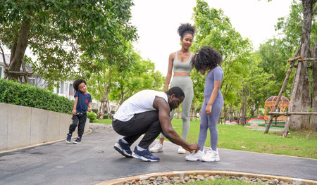 Portrait of Happy African American smiling family resting and having fun after workout outdoors, wearing sports clothes. father, mother and child daughterの写真素材