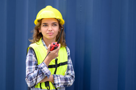 container operators women wearing helmets and safety vests control via walkie-talkie workers in...