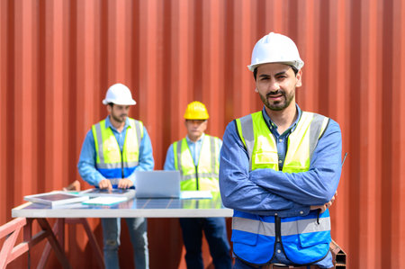 Portrait ofÂ logistic staff workers wearing white helmet and safety vests in cargo container...