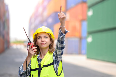 container operators women wearing helmets and safety vests control via walkie-talkie workers in container yards. Cargo Ship Import Export Factory Logistic.の写真素材