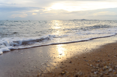 Seawater soft wave crashing on sandy beach seaside in summer on sunset time. summer vacation activity background concept.の写真素材