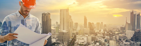 Double exposure image of construction engineer manager workers in orange hardhat and looking layout plan standing during overlay with cityscape on backgroundの写真素材