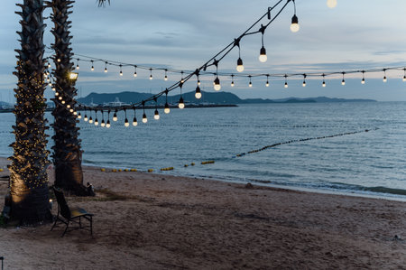 light bulbs on string wire decoration at the party event festival on the beach at sunset. Outdoor holiday background. Copy spaceの写真素材