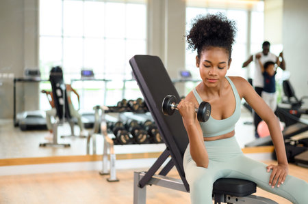Sporty fitness African American woman working out with dumbbells strength and strength endurance at...