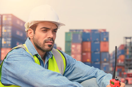Portrait of Container operator holding walkie talkie at Container cargo site checkup goods in...