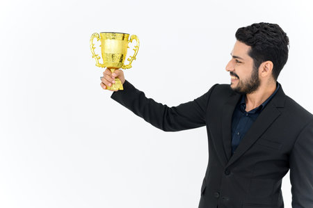 Portrait of Winning businessman celebrating with trophy award for success in business isolated on white background. Successful employee holds golden cup. Looking at the cameraの写真素材