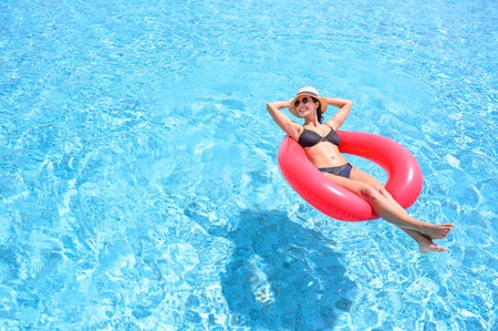 Summer vacation concept. Young beautiful woman in bikini wear hat and sunglasses relaxing in...