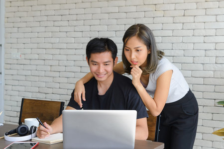 Young Asian couples wear casual clothing while working at home. Couples working with computer laptops in white roomの写真素材