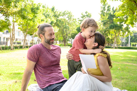 Happy mother day. Children boy congratulating mum and giving his postcard. Happy family father, mother and son in parkの写真素材