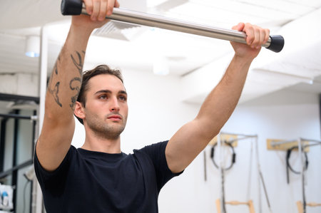 A young man training pilates using reformers machine during class in modern fitness studio