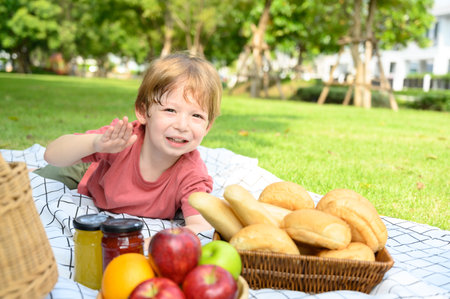 Happy children lying down on picnic fabric with food for picnic in nature on a summer day. little boy genuine emotions.の写真素材