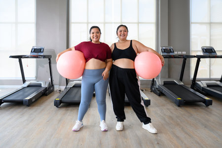 Two overweight women exercise workout in gym. Plus size woman training with fitball. Weight loss workout, healthy lifestyle conceptの写真素材