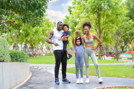 Portrait of Happy African American smiling family resting and having fun after workout outdoors, wearing sports clothes. father, mother and child daughterの写真素材