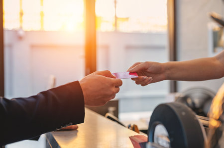 Close-up receptionist hand taking room key card during check-in process at the hotel counter. Business travelling guest receiving room accessの写真素材