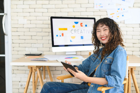 Asian female artist drawing something on graphic tablet. graphic designer working at office. Looking at cameraの写真素材