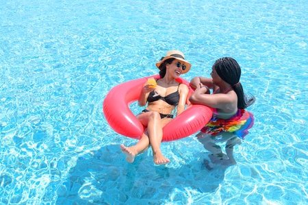 Two woman enjoying in swimming pool. Summer holiday idyllic. Summer vacation concept
