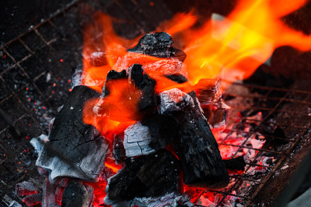 Close-up of burning charcoal with bright orange flames in a barbecue grillの写真素材