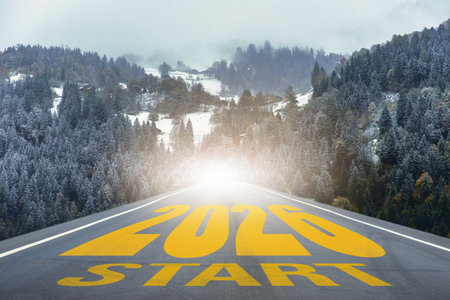 Straight road leading into snowy forest mountains with large text 2026 START. Perfect for business strategy, achievement, planning, and creative projects about new beginnings and opportunitiesの写真素材