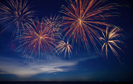 Stunning fireworks illuminate the night sky over the ocean, symbolizing celebration, hope, and the...