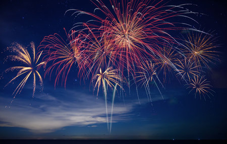 Stunning fireworks illuminate the night sky over the ocean, symbolizing celebration, hope, and the...