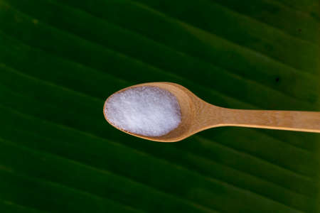 Sea salt in a wooden spoonf, nature background.
