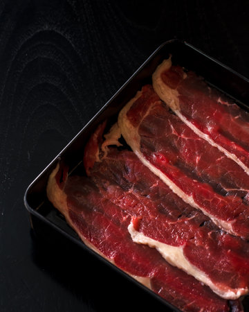 A tray of meat is displayed on a black background. The meat is cut into strips and he is freshの写真素材