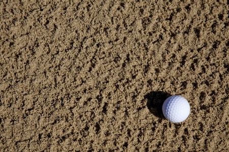 a golfball lying in a sand bunker on a golf courseの写真素材