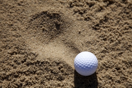 a golfball landing in a sand bunker on a golf courseの写真素材