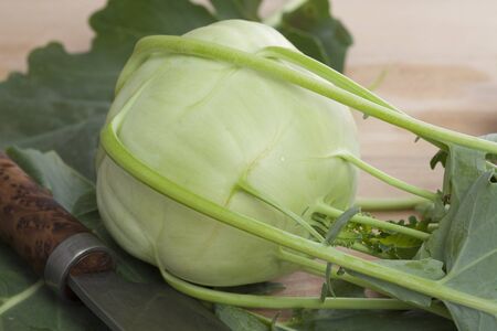 Fresh Kohlrabi on wooden board with big knifeの写真素材