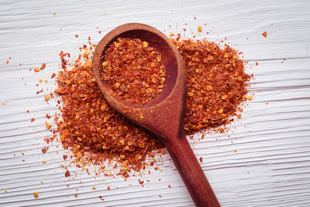 Ground hot thai chilli powder and flakes on a white wooden background.の写真素材