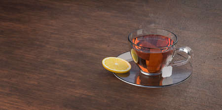 Cup of tea on wooden table. Glass cup with teabag.  Black, brown hot tea. 3d rendering.の写真素材