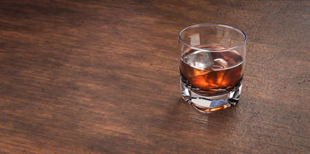 Glass of scotch whiskey and ice. Whisky, bourbon, brandy  or rum on wooden  restaurant table. Glass with alcohol drink.の写真素材