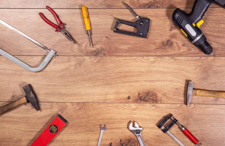Tools on wooden table top view. Handicraft , engineering and handyman kit on wooden background seen from abowe. Copy space frame on wood.の写真素材