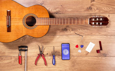 Luthier table top view with classical guitar and tools. Craftsman wooden desk flatlay view with...