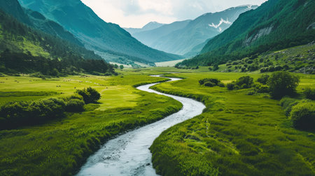 a winding river cutting through a verdant valley surrounded by mountainsの素材
