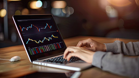 analyzing stock market trends and investment opportunities on a laptop, aiming for financial growthの素材