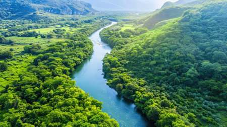 a winding river cutting through a verdant valley surrounded by mountainsの素材
