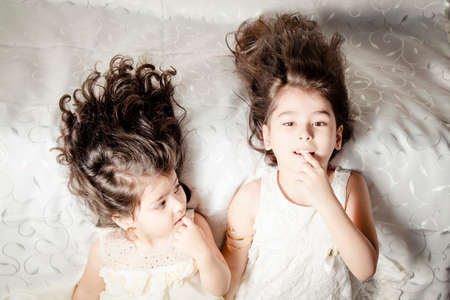 Little sister on Silky bed inside bedroomの写真素材