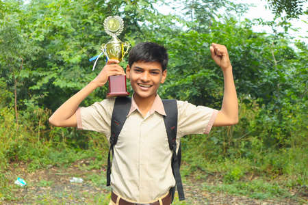 Clever schoolboy raising his trophy as a winner in school competition.の写真素材