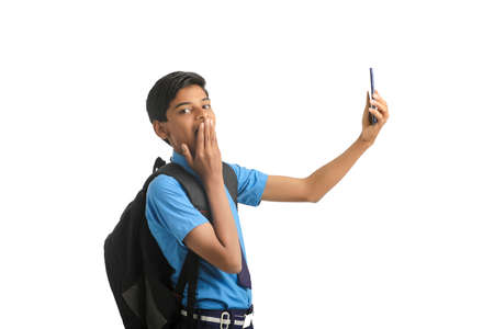 indian school boy using smartphone on white background.の写真素材